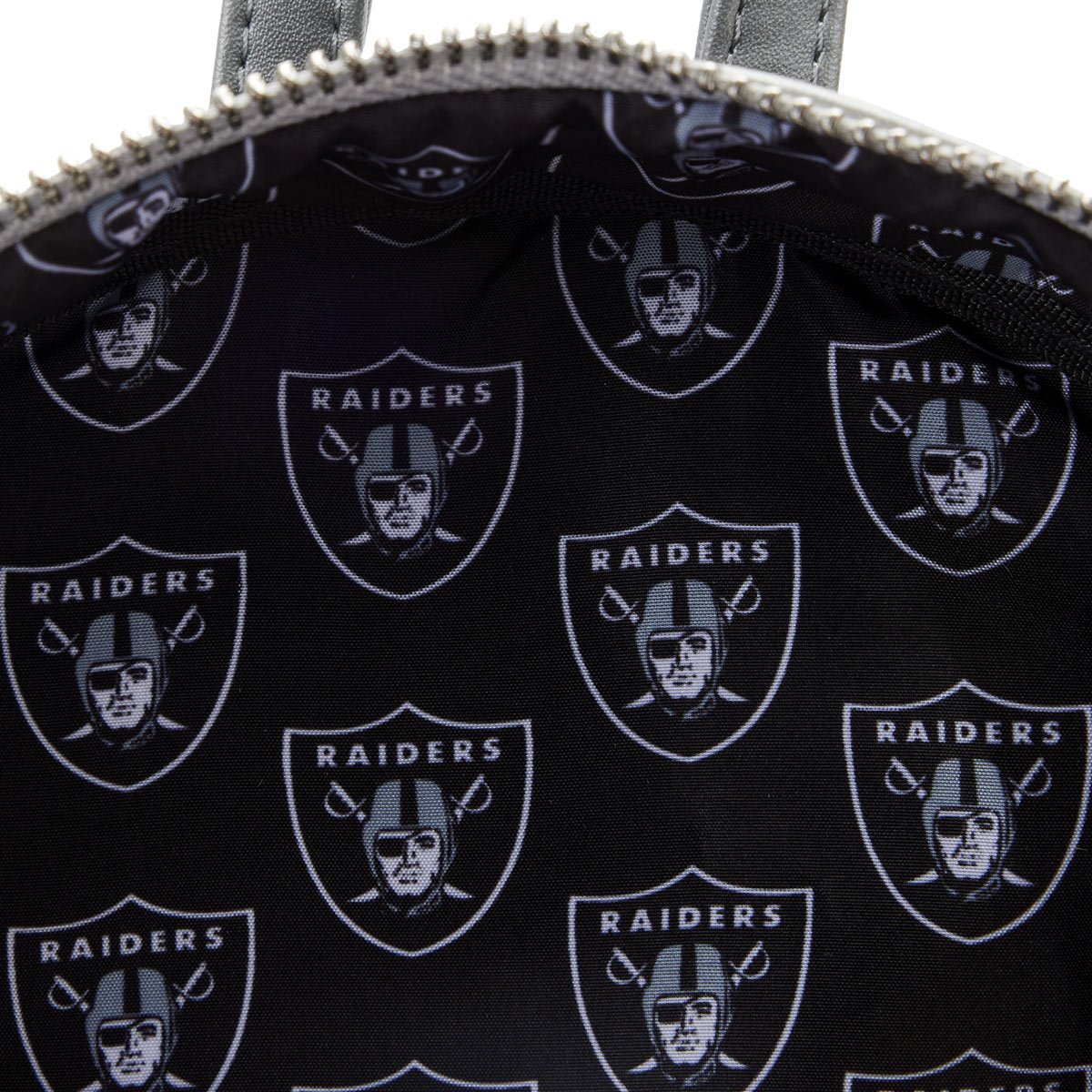Close-up of a bag with repeated Raiders logo on a black background