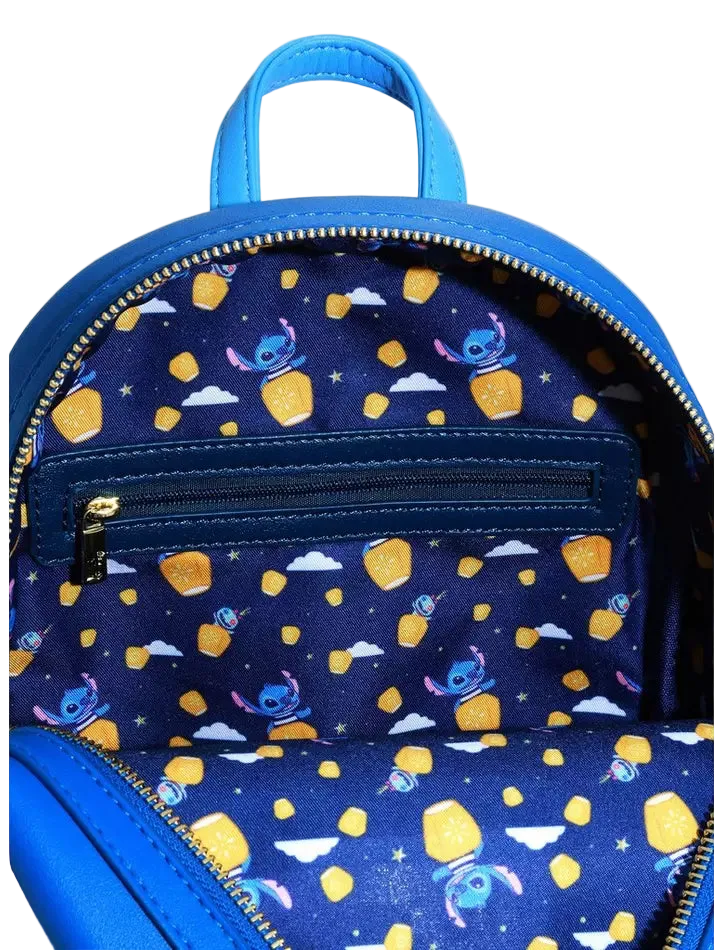 Close-up of the inside of a blue backpack, showing a navy patterned lining with cartoon characters and yellow star-shaped accents, plus a top handle and zipper.