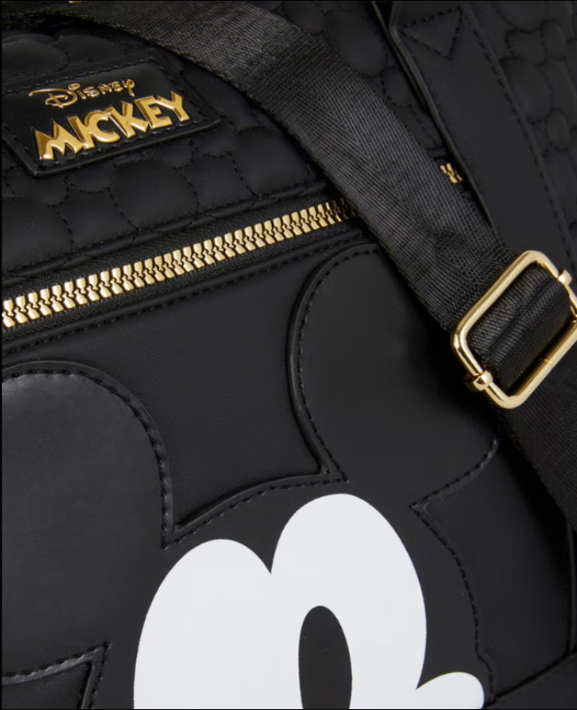 Black backpack with gold zipper and white Mickey Mouse design, featuring Disney logo.