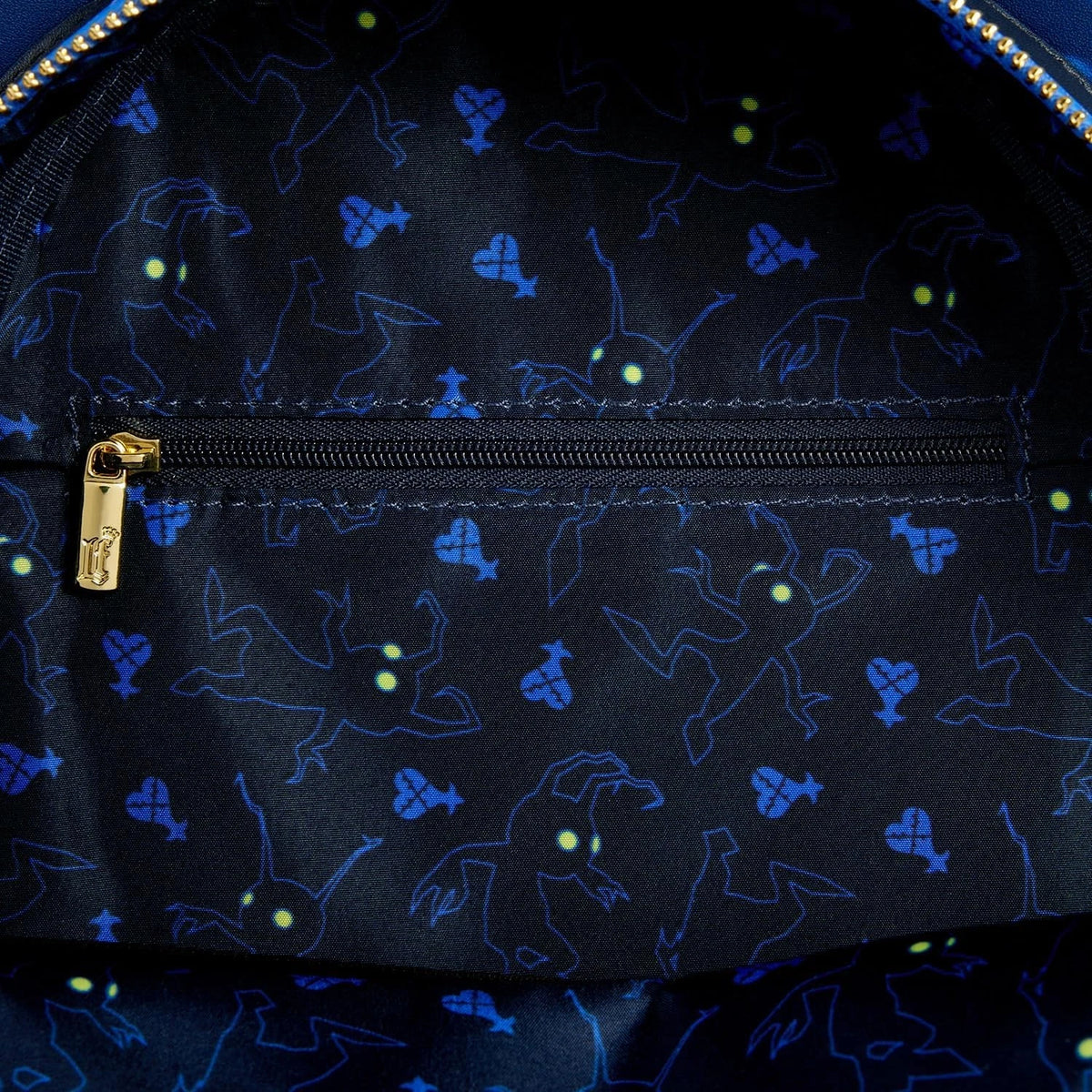 Close-up of a dark fabric with blue glowing patterns and a gold zipper.