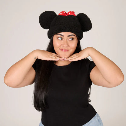 Person wearing a black knit hat with red accents and black ears, posing against a plain background.