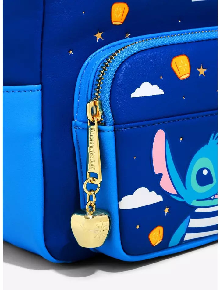 Close-up of a blue backpack or bag with a front zip pocket, gold zipper pull, and cartoon character print on a blue background with stars and clouds.
