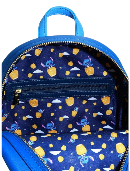 Close-up of the inside of a blue backpack, showing a navy patterned lining with cartoon characters and yellow star-shaped accents, plus a top handle and zipper.