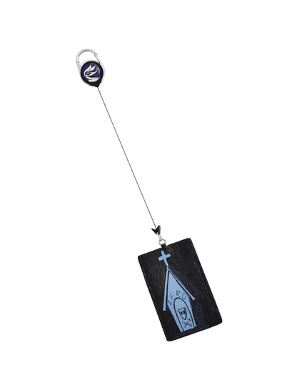 A black rectangular card holder or ID tag with a light blue coffin-shaped graphic and a small cross, attached to a black retractable badge reel with a silver key ring, shown on a plain light gray background.