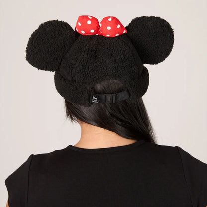 Black fleece beanie with large ears and a red polka dot bow on a plain background