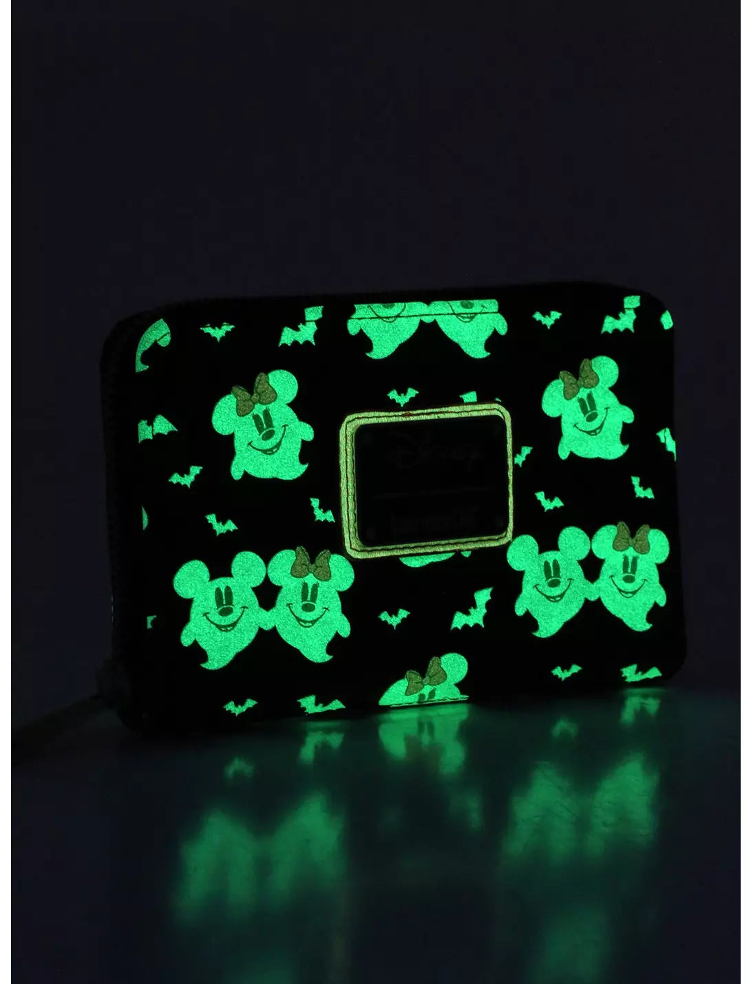 A black zip-around wallet with a glowing green repeating Mickey Mouse and bat pattern, shown on a dark reflective surface.