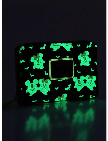 A black zip-around wallet with a glowing green repeating Mickey Mouse and bat pattern, shown on a dark reflective surface.