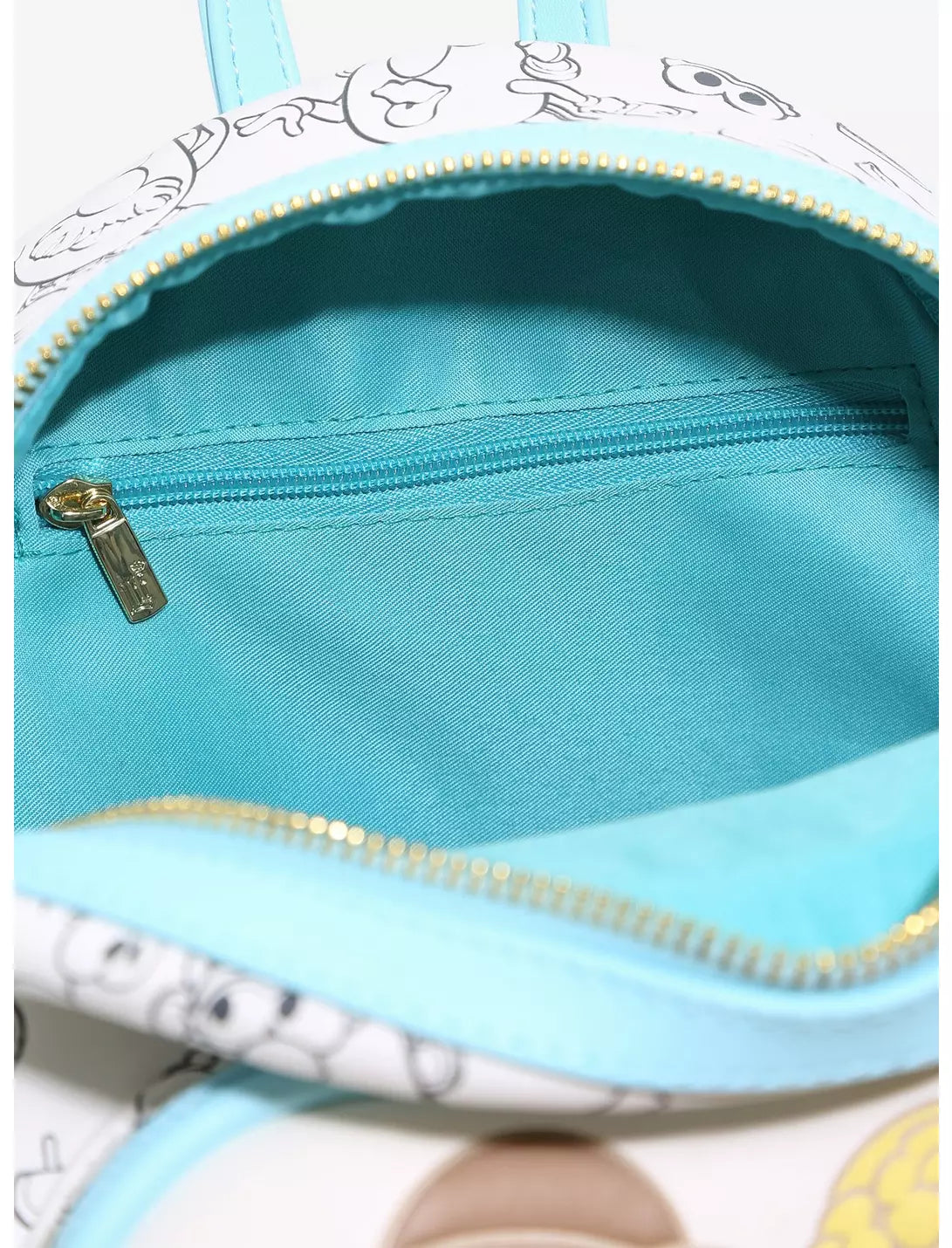 Close-up of the interior of a small backpack or pouch with a light blue lining, a white exterior printed with cartoon faces, and gold-tone zippers.