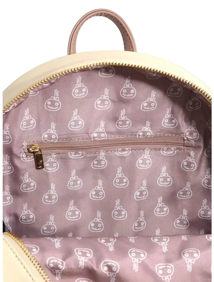 Close-up of the interior of a backpack showing a dusty pink patterned lining with a repeating white cartoon bunny design, a zippered pocket, and a cream-colored top handle and trim.