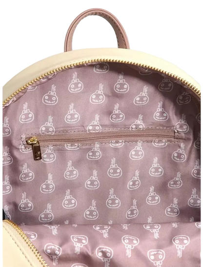 Close-up of the interior of a backpack showing a dusty pink patterned lining with a repeating white cartoon bunny design, a zippered pocket, and a cream-colored top handle and trim.