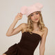 Woman wearing a pink beret and brown dress against a plain background