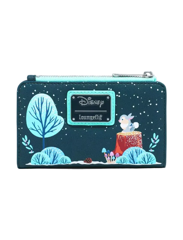 A Loungefly Disney Lilo & Stitch winter-themed zip-around wallet. The dark teal wallet features a printed design of Stitch on a tree stump, a glowing blue tree, and a snowy night sky, with a turquoise nameplate displaying the Disney Loungefly brand.