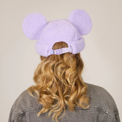 Person wearing a lavender fleece-lined hat with bunny ears on a beige background