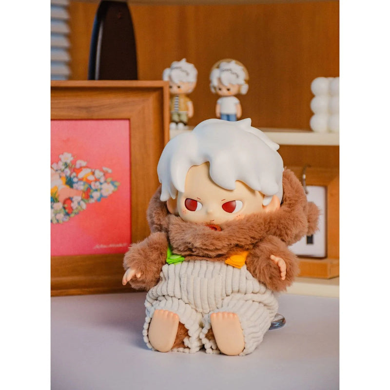 Plush toy with white hair and red eyes on a light surface with a wooden frame and decorative items in the background.