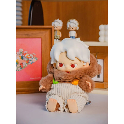 Plush toy with white hair and red eyes on a light surface with a wooden frame and decorative items in the background.