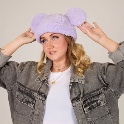 Person wearing a light purple fleece hat with bear ears, standing against a plain background