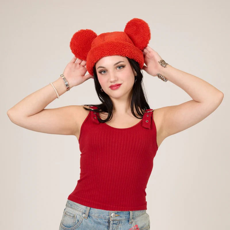 Woman wearing a red fleece hat with bear ears against a plain background