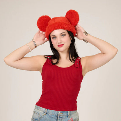 Woman wearing a red fleece hat with bear ears against a plain background
