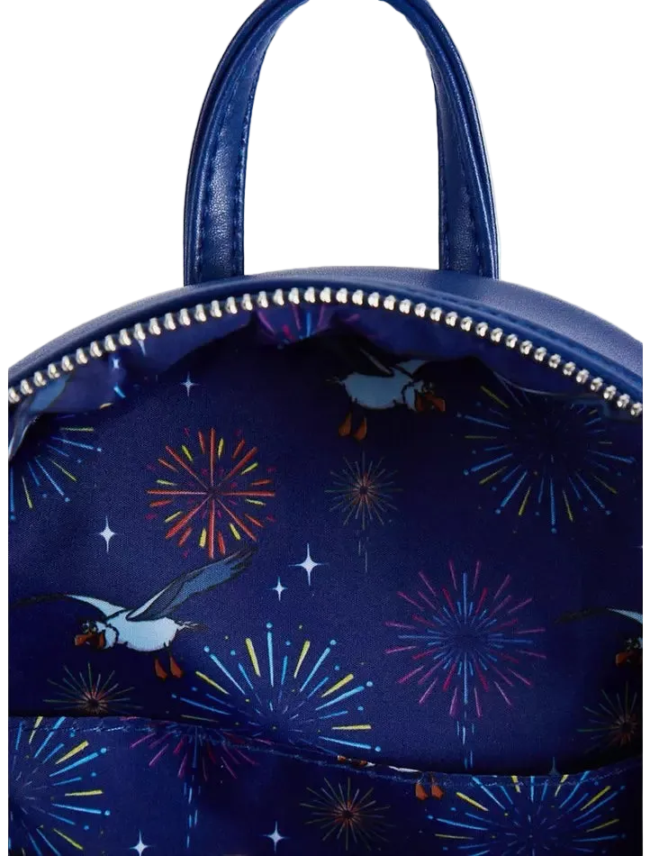 A close-up of a navy blue backpack featuring a printed pattern of puffins flying past colorful fireworks and white stars, with silver studs along the zipper.