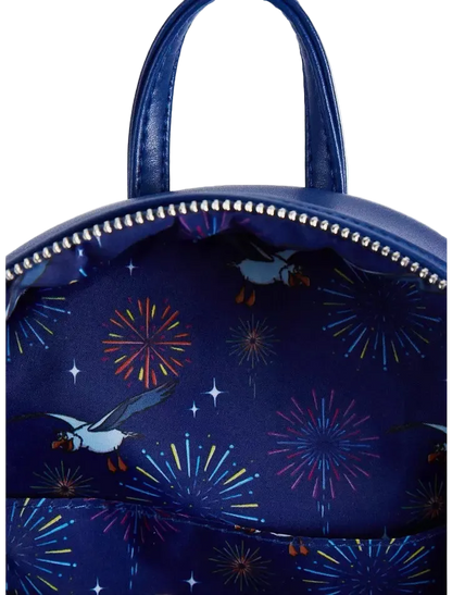 A close-up of a navy blue backpack featuring a printed pattern of puffins flying past colorful fireworks and white stars, with silver studs along the zipper.