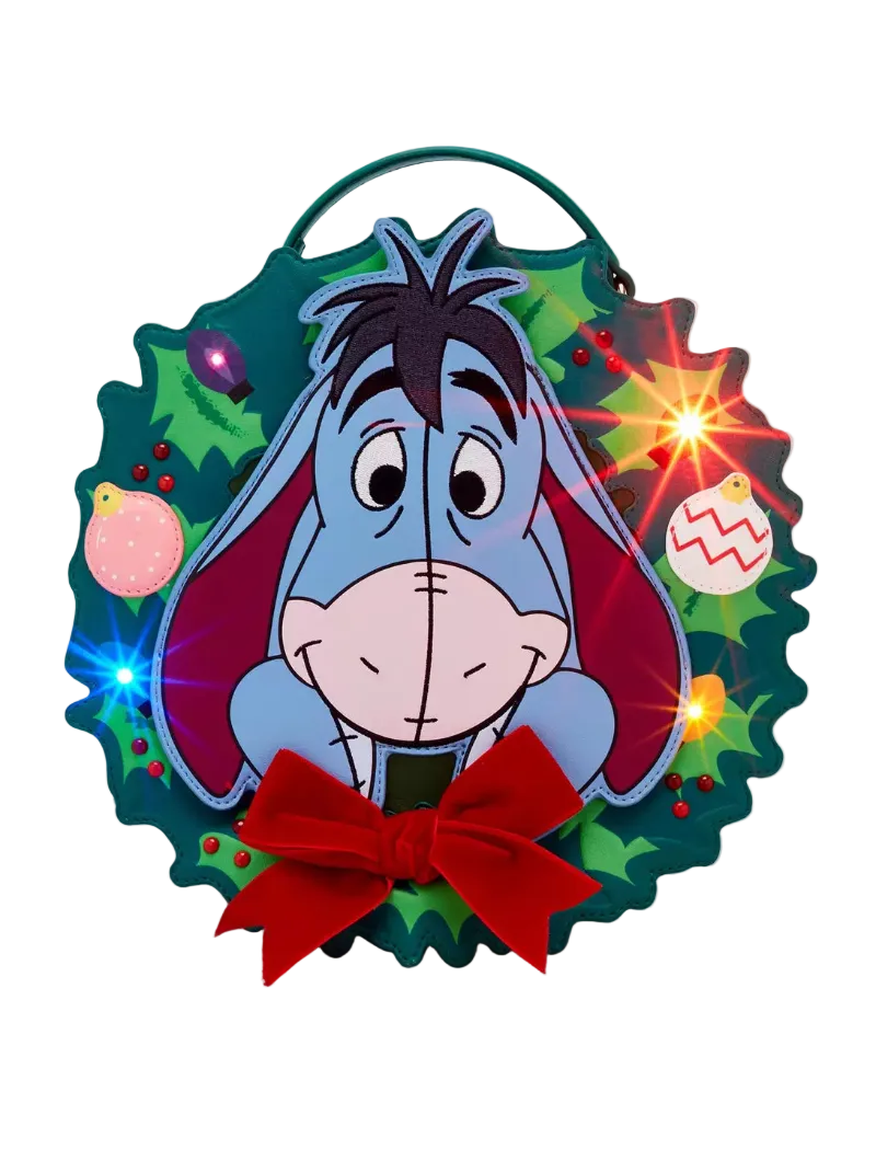 A festive Christmas wreath-shaped wall hanging featuring Eeyore from Winnie the Pooh, with a red bow at the bottom and glowing light effects around the wreath.