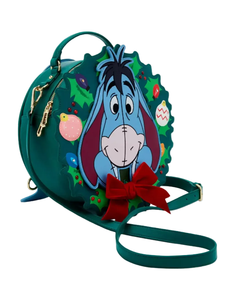 A green holiday-themed mini backpack featuring a 3D Easter egg design of Eeyore the donkey surrounded by Christmas holly and ornaments, with a red bow and matching green strap on a white background.
