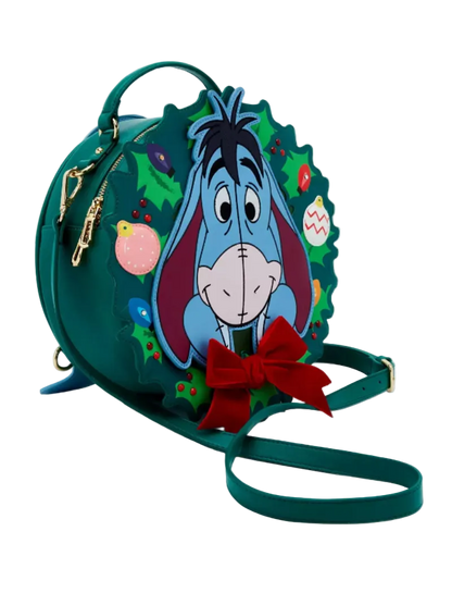 A green holiday-themed mini backpack featuring a 3D Easter egg design of Eeyore the donkey surrounded by Christmas holly and ornaments, with a red bow and matching green strap on a white background.