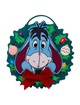 A circular Christmas wreath wall hanging featuring the character Eeyore from Winnie the Pooh, with a red bow at the bottom and colorful ornaments on a white background.