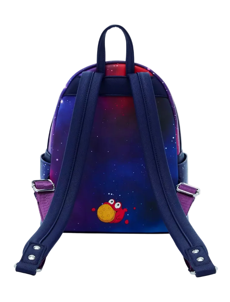 A small backpack shown from the back, featuring a dark blue and purple galaxy print with a small red and yellow cartoon character near the bottom. The backpack has thick navy blue shoulder straps and silver metal buckles on the side straps.
