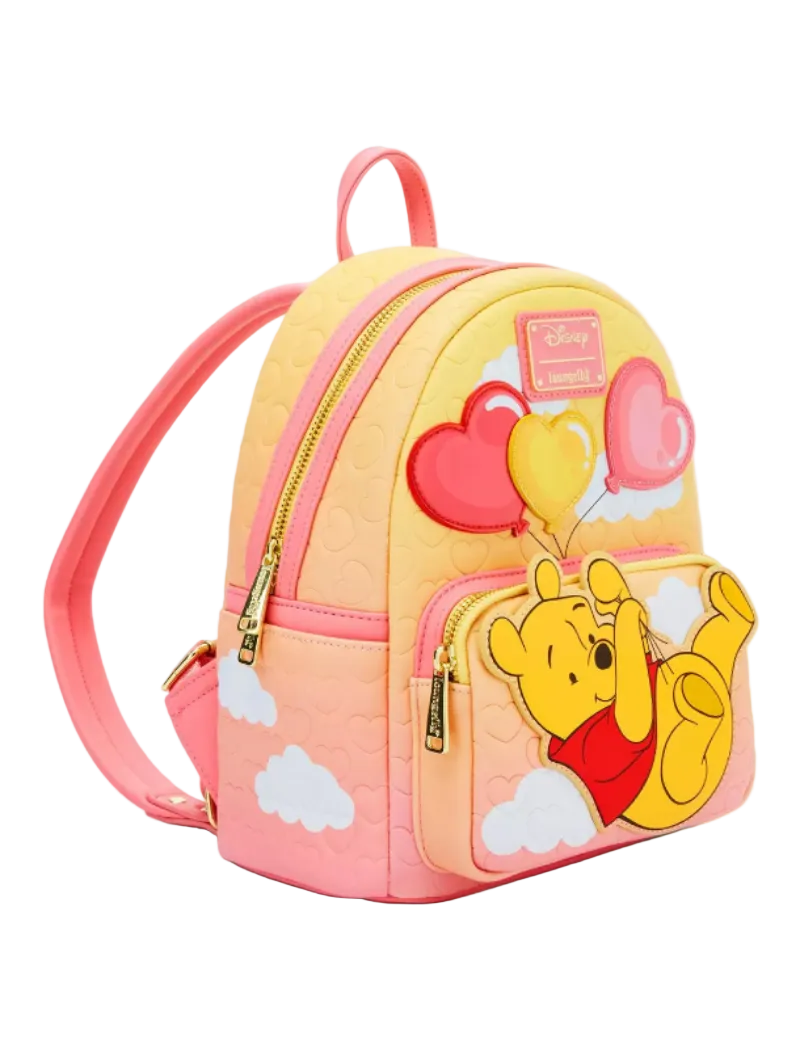 A pastel pink and yellow gradient mini backpack featuring Winnie the Pooh and his balloons on the front pocket, with gold-tone zippers and a Disney patch.