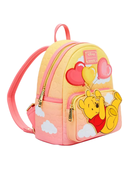 A pastel pink and yellow gradient mini backpack featuring Winnie the Pooh and his balloons on the front pocket, with gold-tone zippers and a Disney patch.