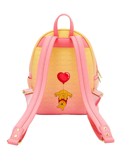 A pink and yellow mini backpack featuring a cute graphic of Winnie the Pooh holding a red heart balloon, shown from the back against a light gray background.