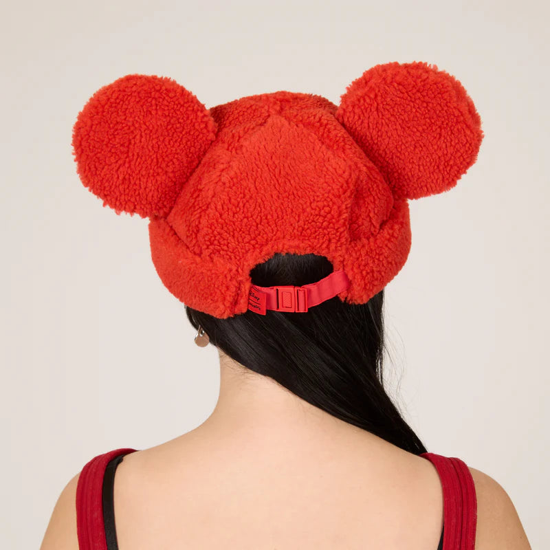 Red fleece beanie with large ears worn by a person on a plain background