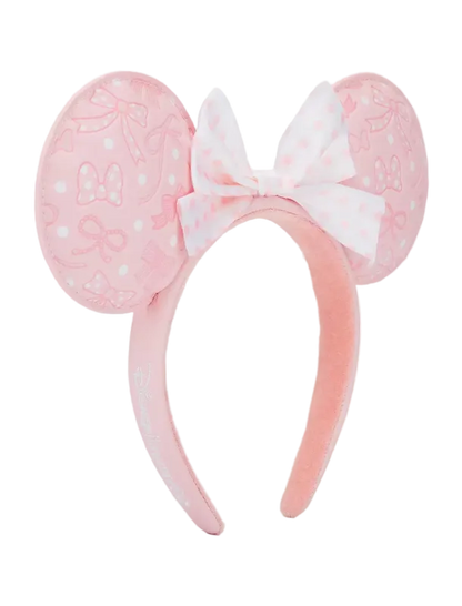 A pink plush headband featuring round mouse ears with bow and polka dot patterns, and a matching bow on the front, shown against a plain white background.