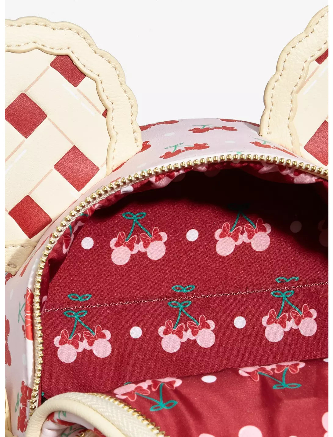 Close-up of a red fabric with cherry pattern and beige checkered design on top.