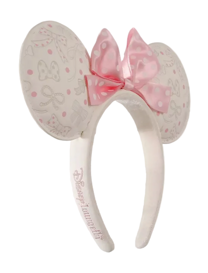 A pair of Minnie Mouse-themed mouse ears headband featuring a pink polka-dot bow and embossed Minnie Mouse designs on a light cream background, with 'Disneyanna Fly' embroidered on the band.