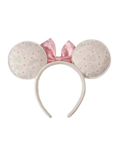 A headband with large round mouse ears in a light pink and white patterned fabric, featuring a pink satin bow on top, shown against a plain white background.