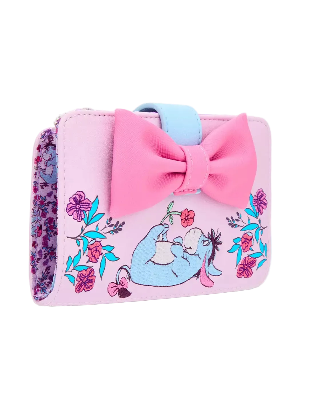 A pink faux-leather wallet featuring a large pink bow, a light blue strap, and an illustration of Eeyore sitting among colorful flowers. The side of the wallet shows a purple and pink floral pattern.