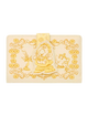A beige faux leather wallet featuring embossed Disney's Beauty and the Beast illustrations, including Belle, the lampstand, and the teapot, with a central gold-tone strap closure.