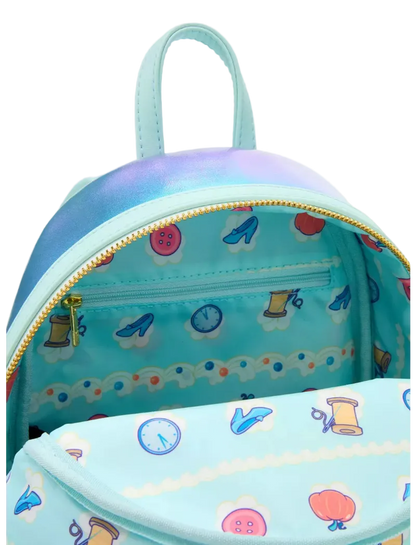 A light blue mini backpack with a colorful sewing-themed print inside and on the front pocket, featuring a gold zipper and a matching top handle.