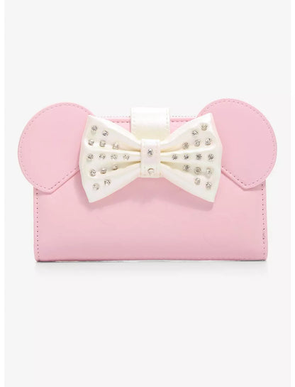A pink faux-leather clutch bag featuring Minnie Mouse-inspired round ears and a large white bow embellished with rhinestones, shown against a plain white background.