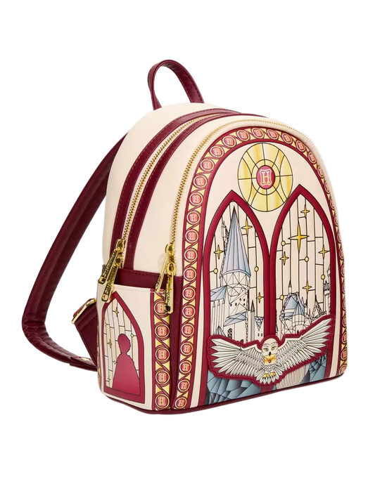 A small backpack with a cream and burgundy design inspired by stained glass, featuring gold zippers and a printed illustration of a cathedral, a dove, and a silhouette.