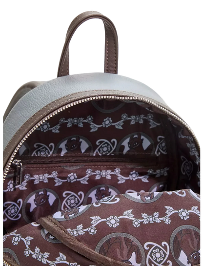 Close-up of the interior of a small backpack with a light gray exterior and a brown patterned lining featuring white floral and circular motifs.