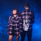 Two people wearing matching plaid shirts with a blue gradient background