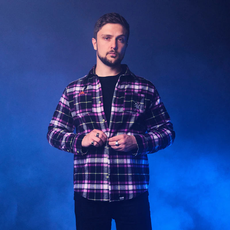 Man wearing a purple plaid shirt against a blue background