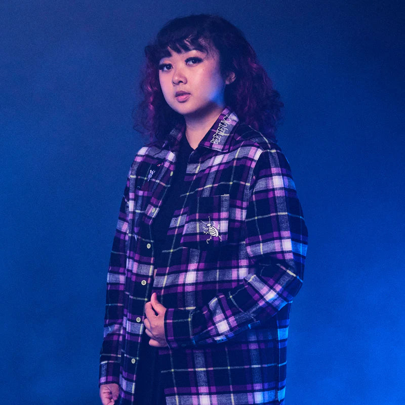 Person wearing a purple and black plaid shirt against a blue background