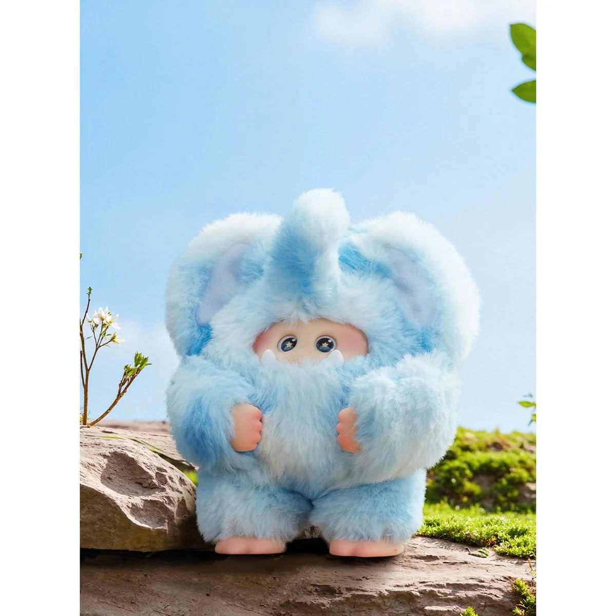Plush toy with blue fur sitting on a rock against a clear sky