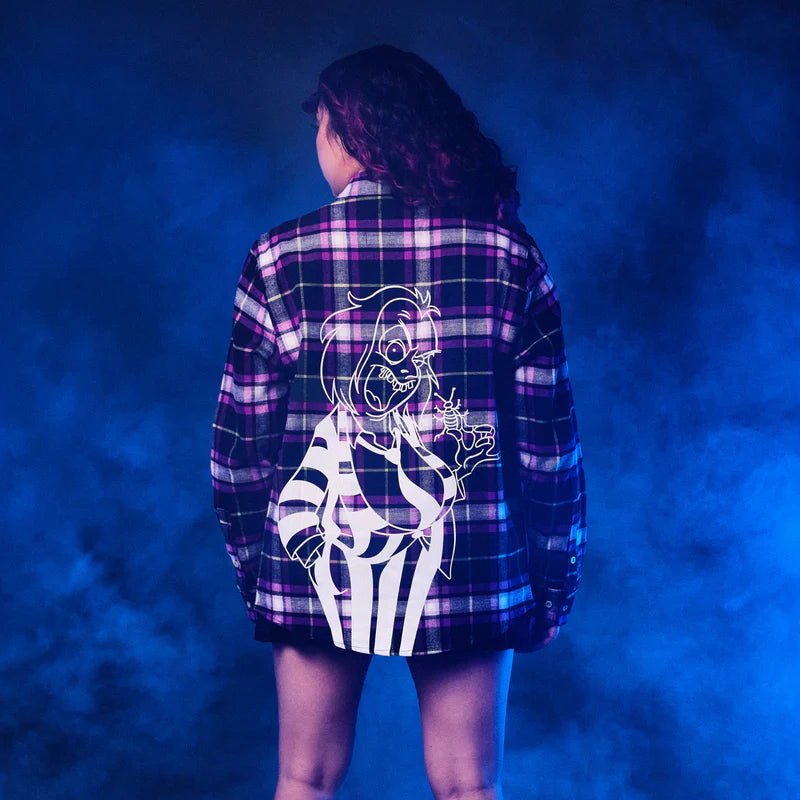 Person wearing a plaid shirt with a skeleton design on the back against a blue background