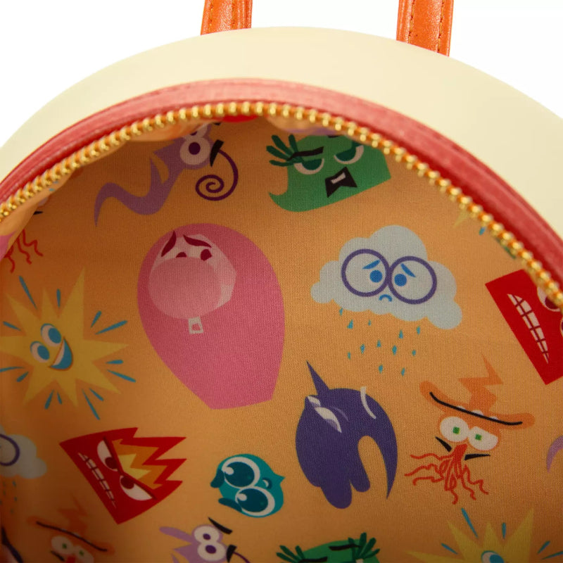 Close-up of a colorful children's backpack with various cartoonish face designs on an orange background.