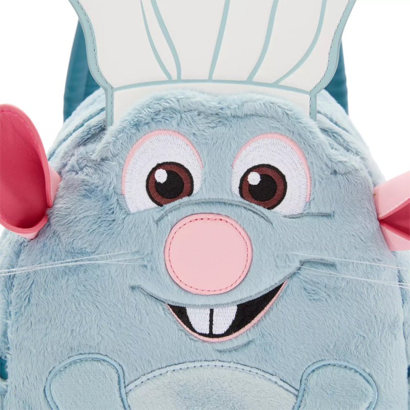 A close-up of a plush character backpack featuring a light blue rabbit face with pink ears, a pink nose, embroidered brown eyes, and a white chef hat on a white background.